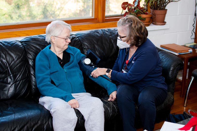 A nurse checks a patient's vitals in their home.