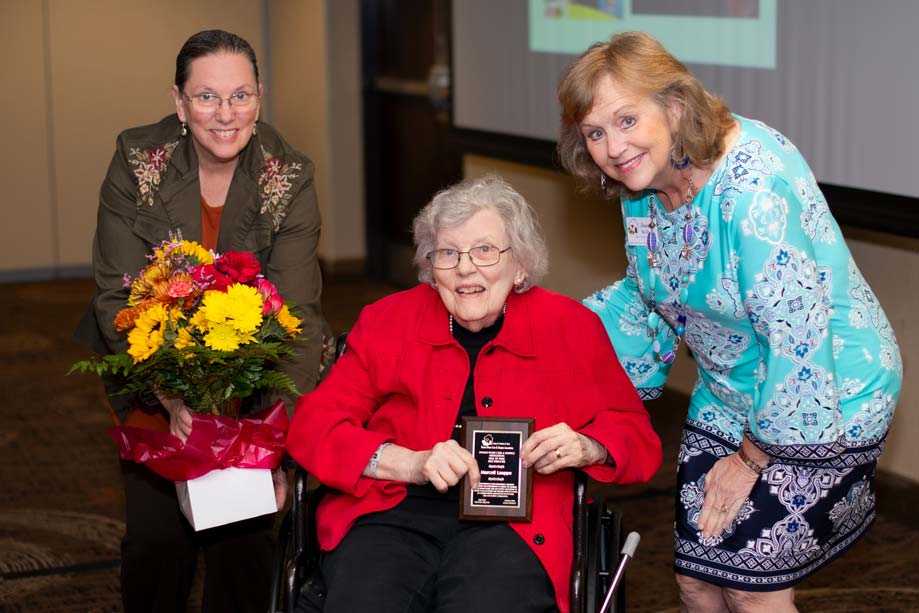 Marceil Lauppe poses with her KHCHA Hall of Fame plaque and two KHCHA representatives.
